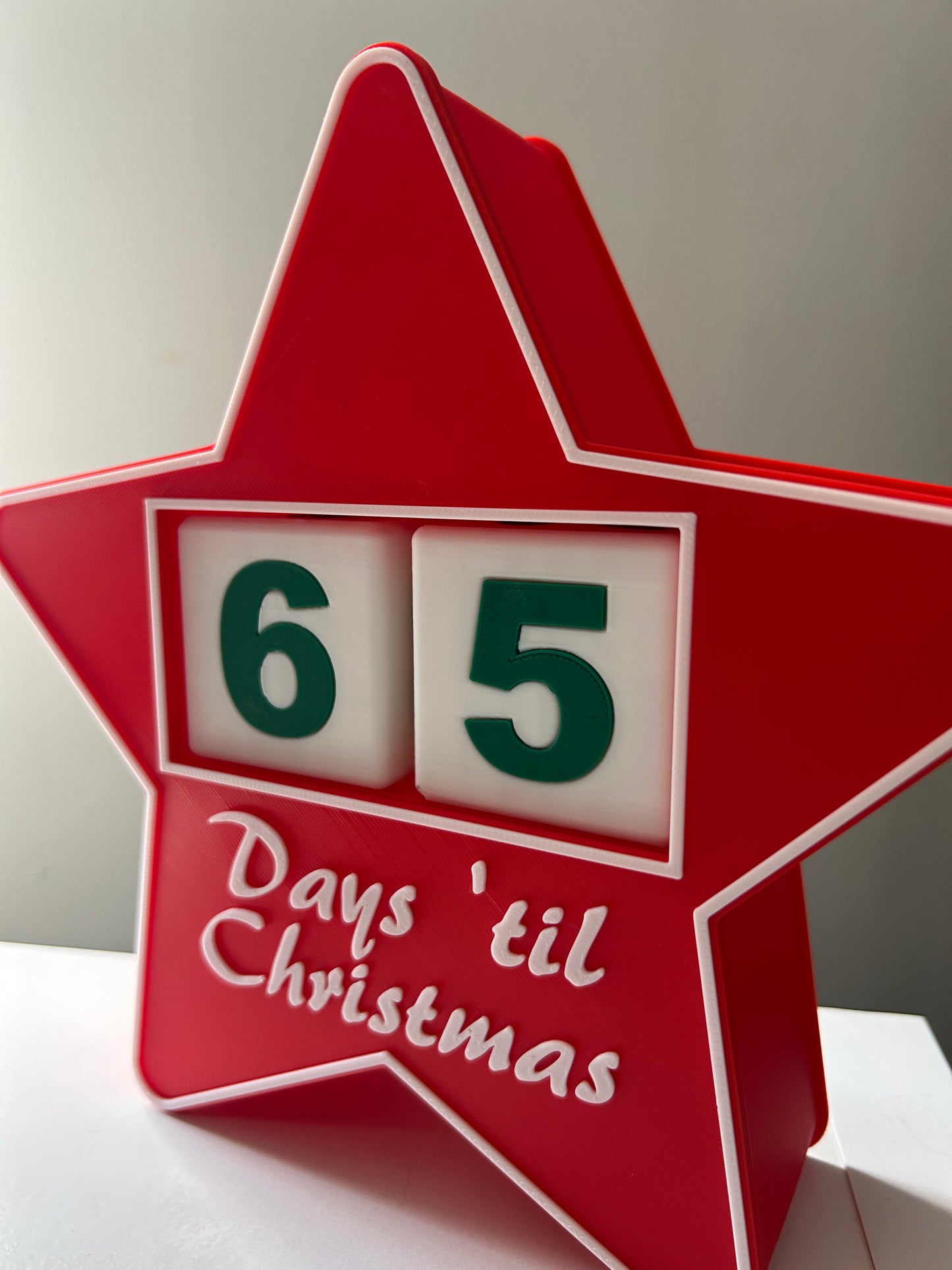 Red star-shaped Christmas countdown calendar with '65 days 'til Christmas' text.
