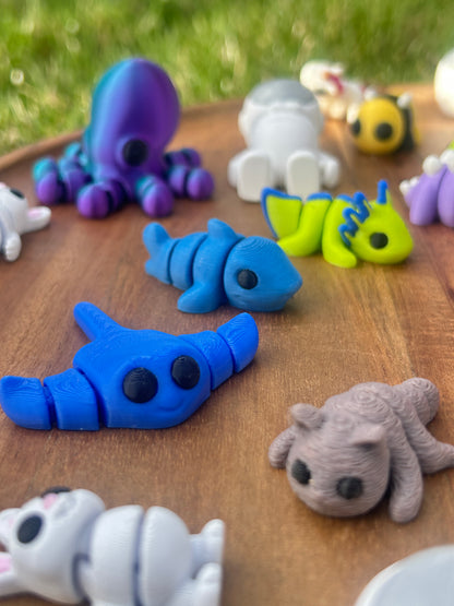 Close up shot of 3D printed Mini Critters including a blue Sting-ray, Octopus, and White Bunny.