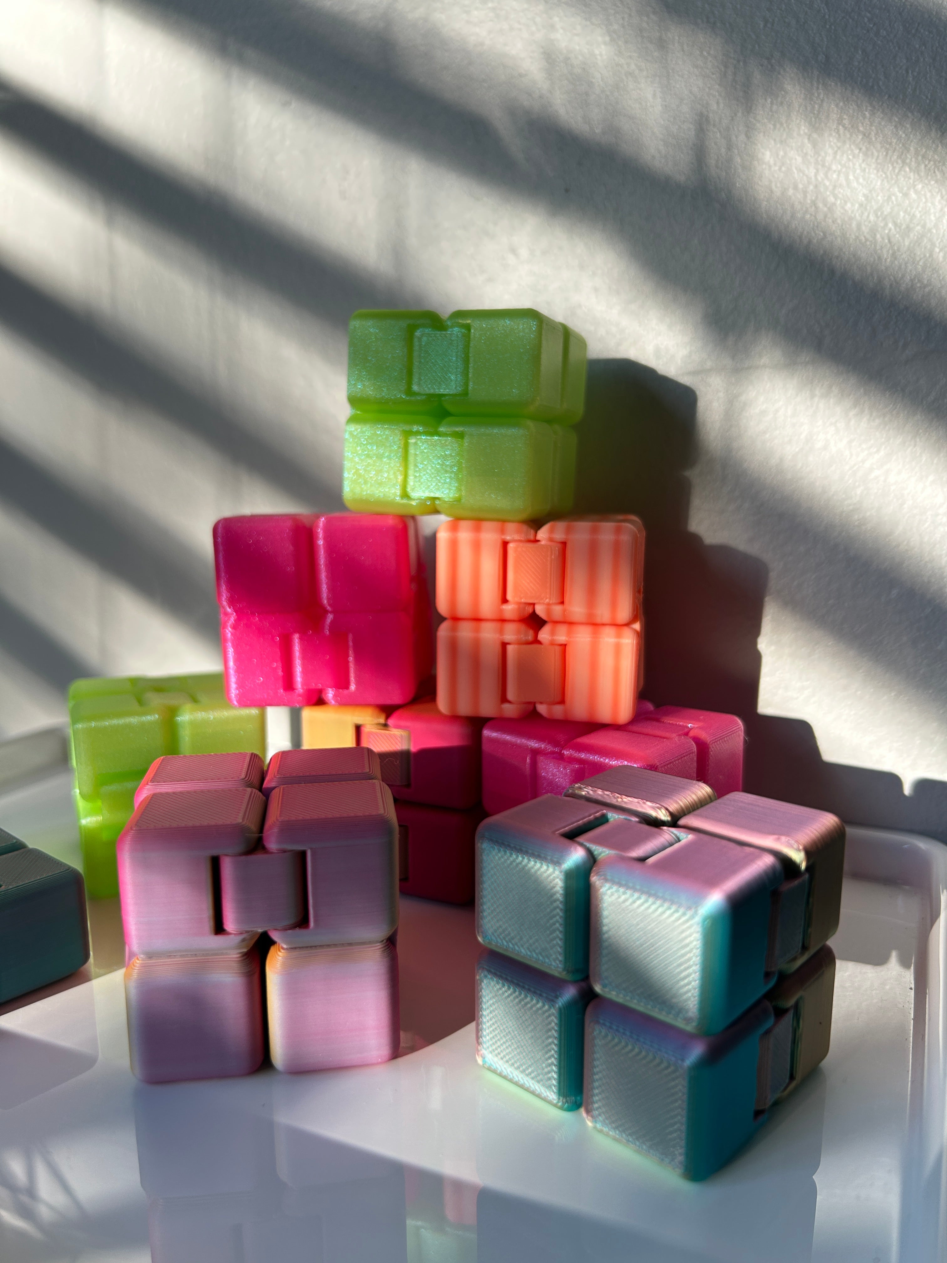 Eight Infinity Cube 3d Print toys (in various colors) stacked in a pyramid shape.