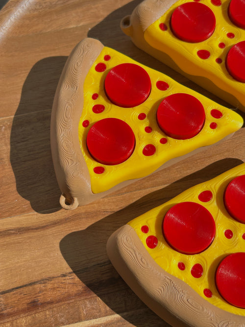 Three Pizza Slice Fidget Clicker Toys on a circular, wooden surface.