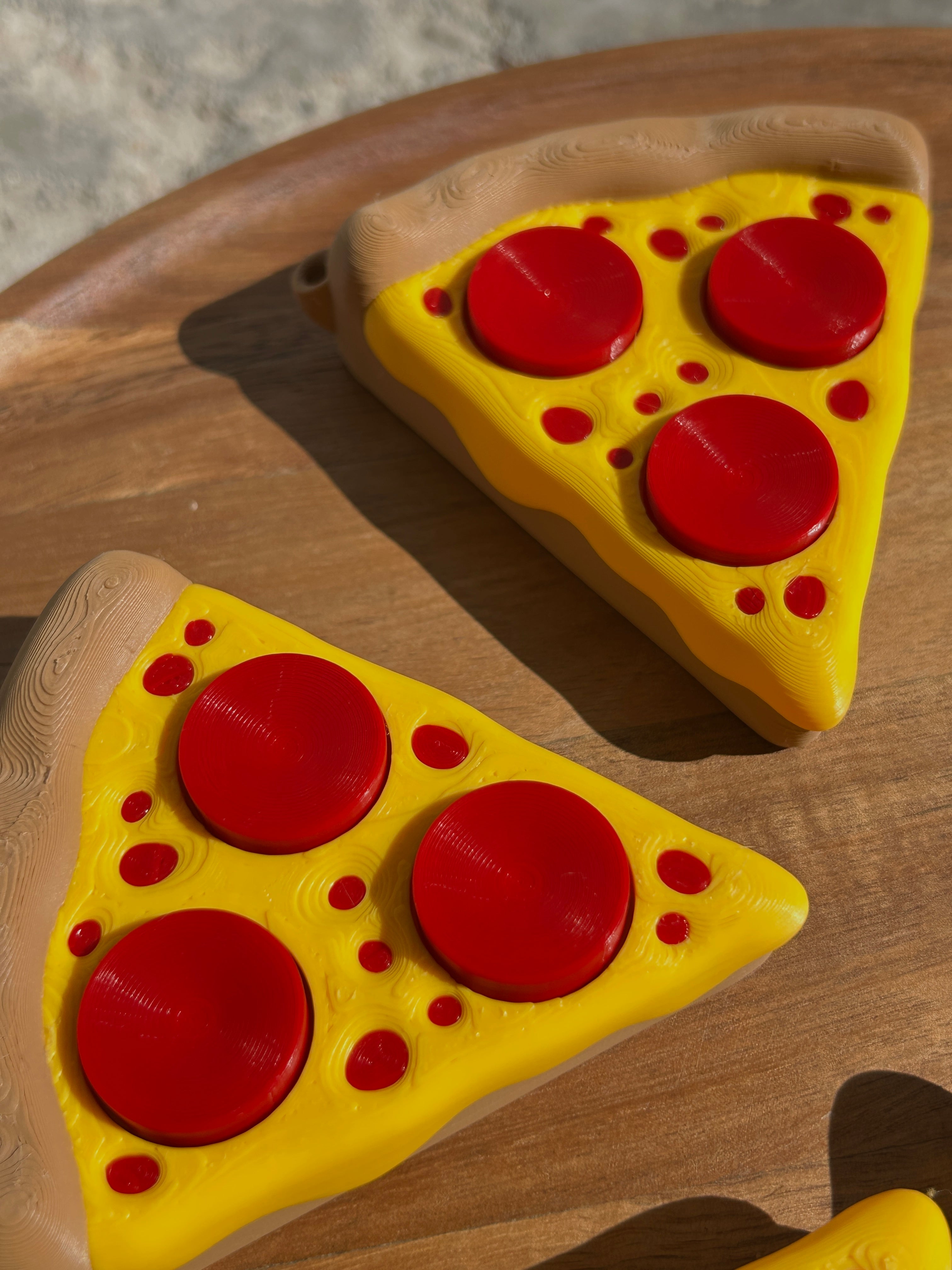 Two Pizza Slice Fidget Clicker Toys on a circular, wooden surface.