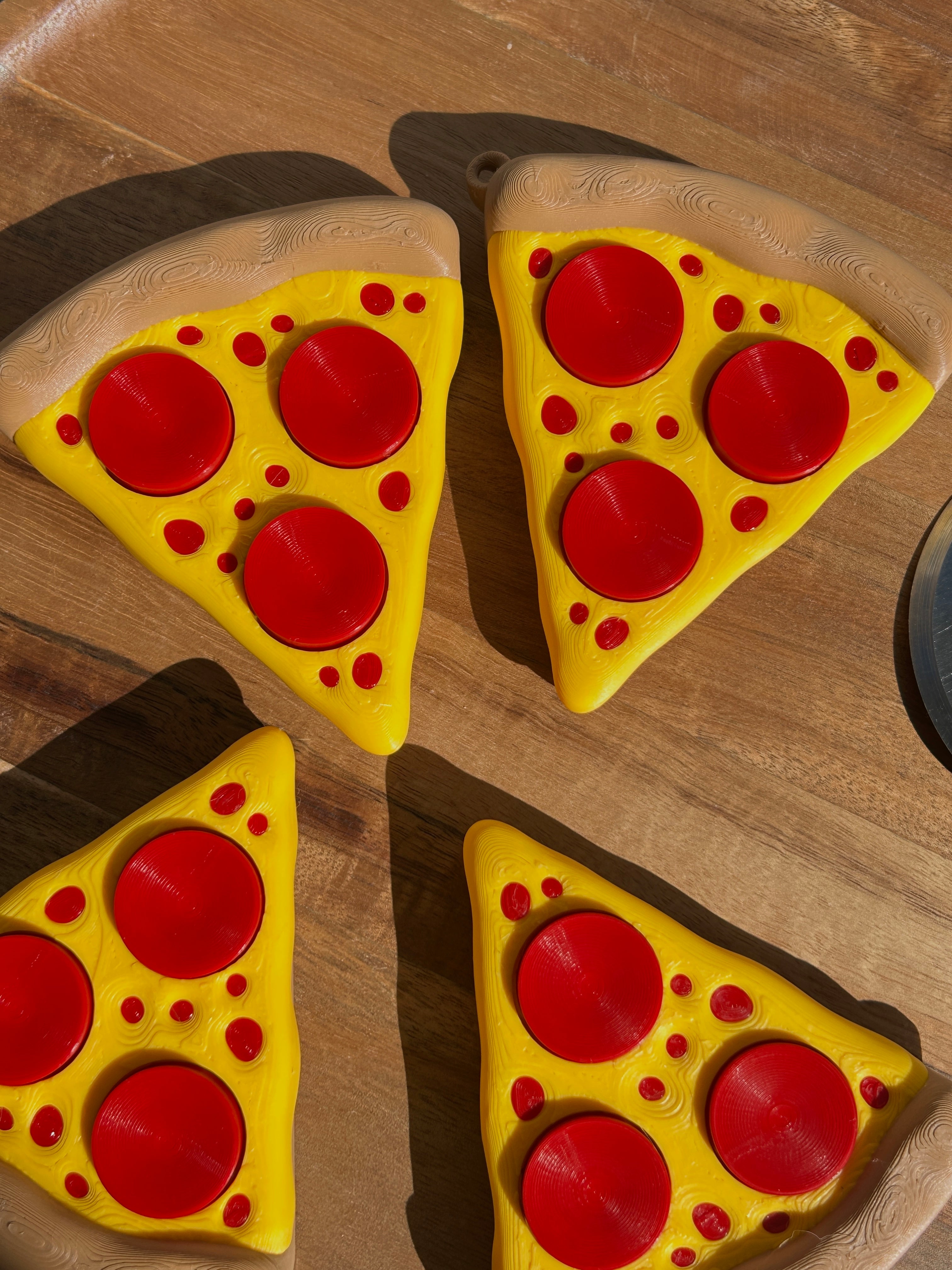 Four Pizza Slice Fidget Clicker Toys on a circular, wooden surface.