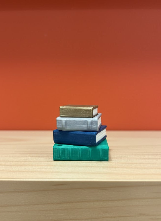 Stack of books on a wooden surface with an orange wall background