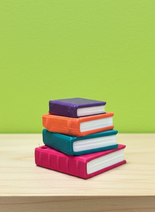 Stack of colorful books on a wooden surface with a green background
