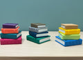 Stacks of colorful books on a wooden surface with a blue background
