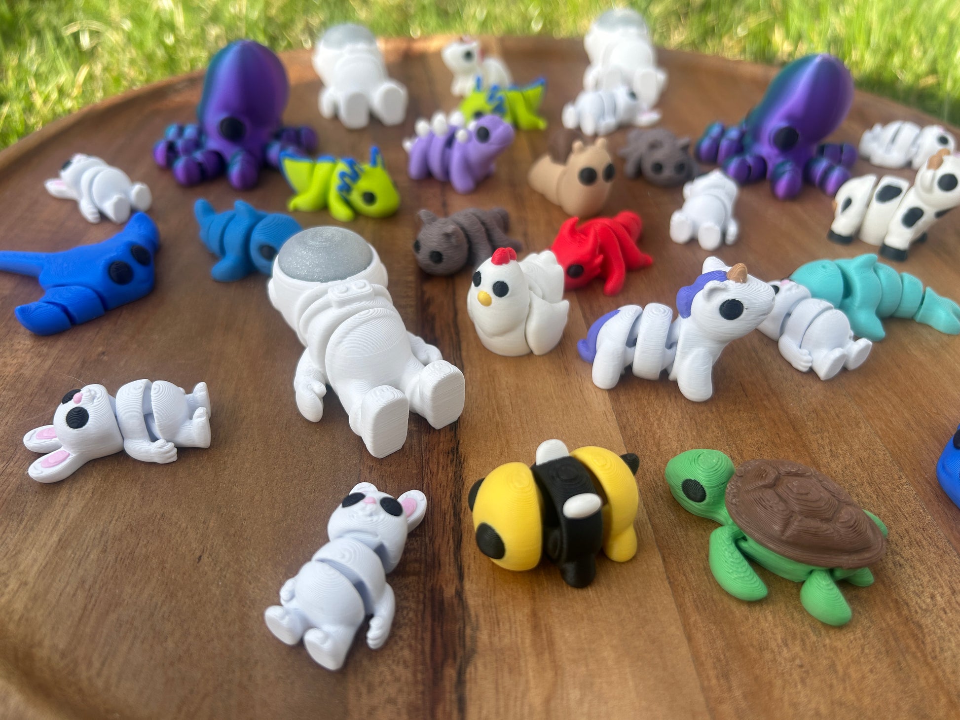 A collection of 3D Printed Mini Critters lays scattered across a circular, wooden platform.