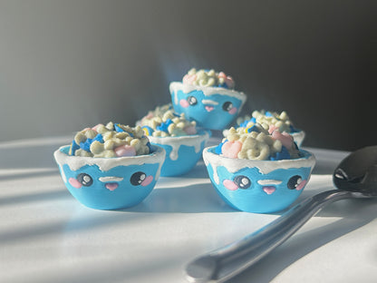 Set of blue 3D printed bowls of cereal with kawaii faces on a light surface with a dark background.