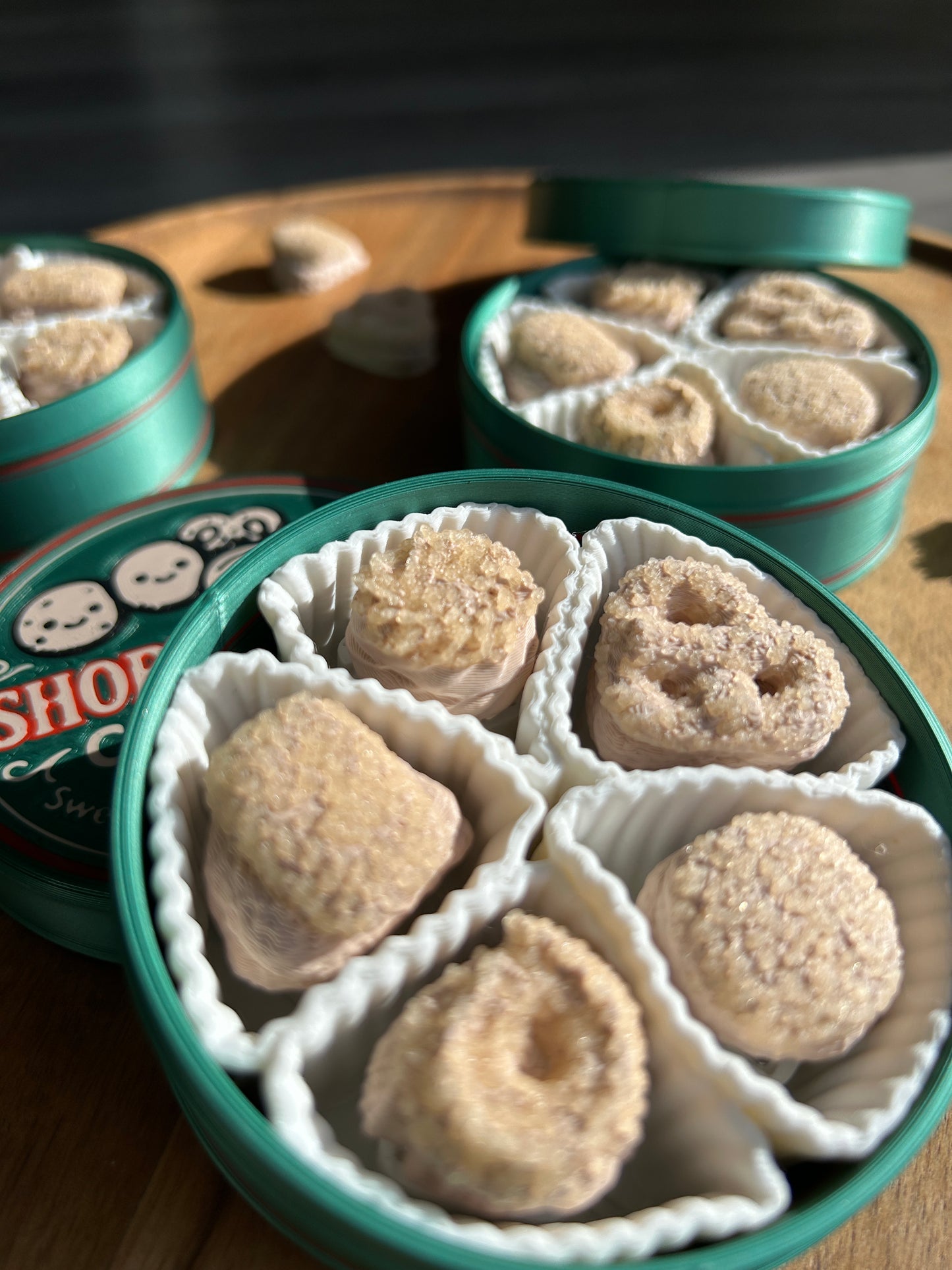 Green Classic Shortbread cookie tins filled with round, beige cookies on a wooden surface.