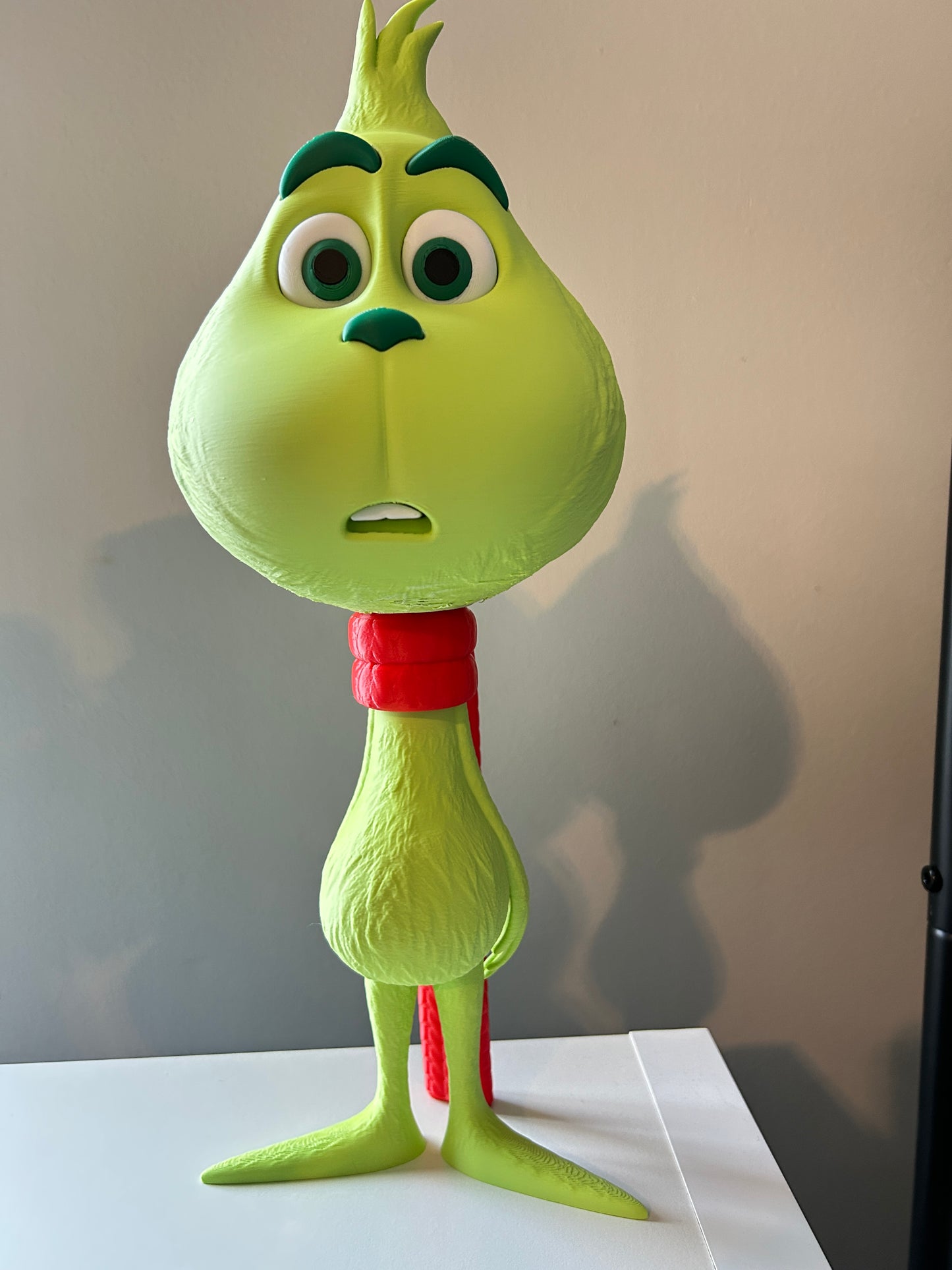 Green Grinch home decoration model with a red scarf on a white background