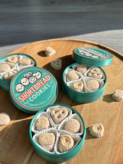 Three open green tins of Shortbread cookies on a wooden surface.